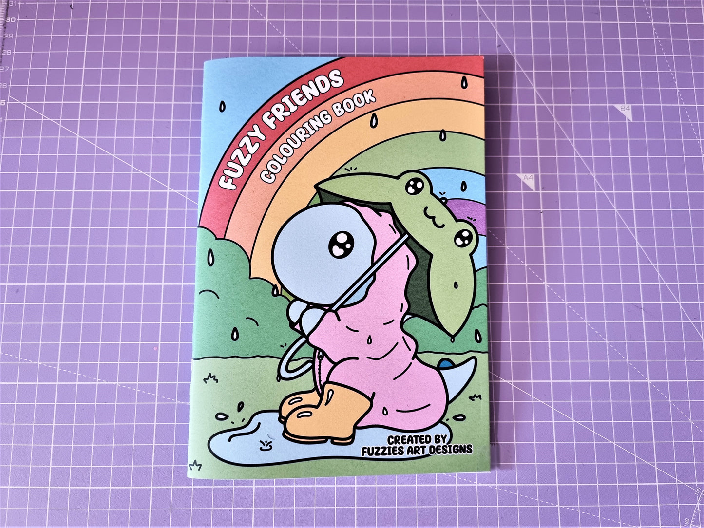 Picture of colouring book with dinosaur playing in the rain on the front